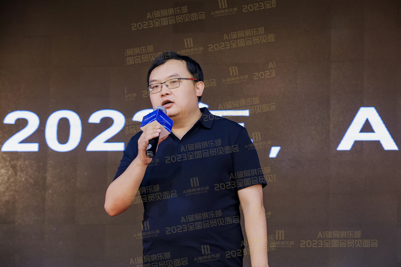 图片展示的是2023年AI破局俱乐部全国会员见面会现场。一位男士身着黑色短袖，手持蓝色麦克风，正在台上演讲。背景为深色，上方有“AI破局俱乐部 2023全国会员见面会”字样，重复多次。画面左侧有“2023”字样，右侧有“A”字样。该图片与文档中介绍的2023年AI破局俱乐部全国会员见面会活动相契合，呈现了活动中的一个场景。