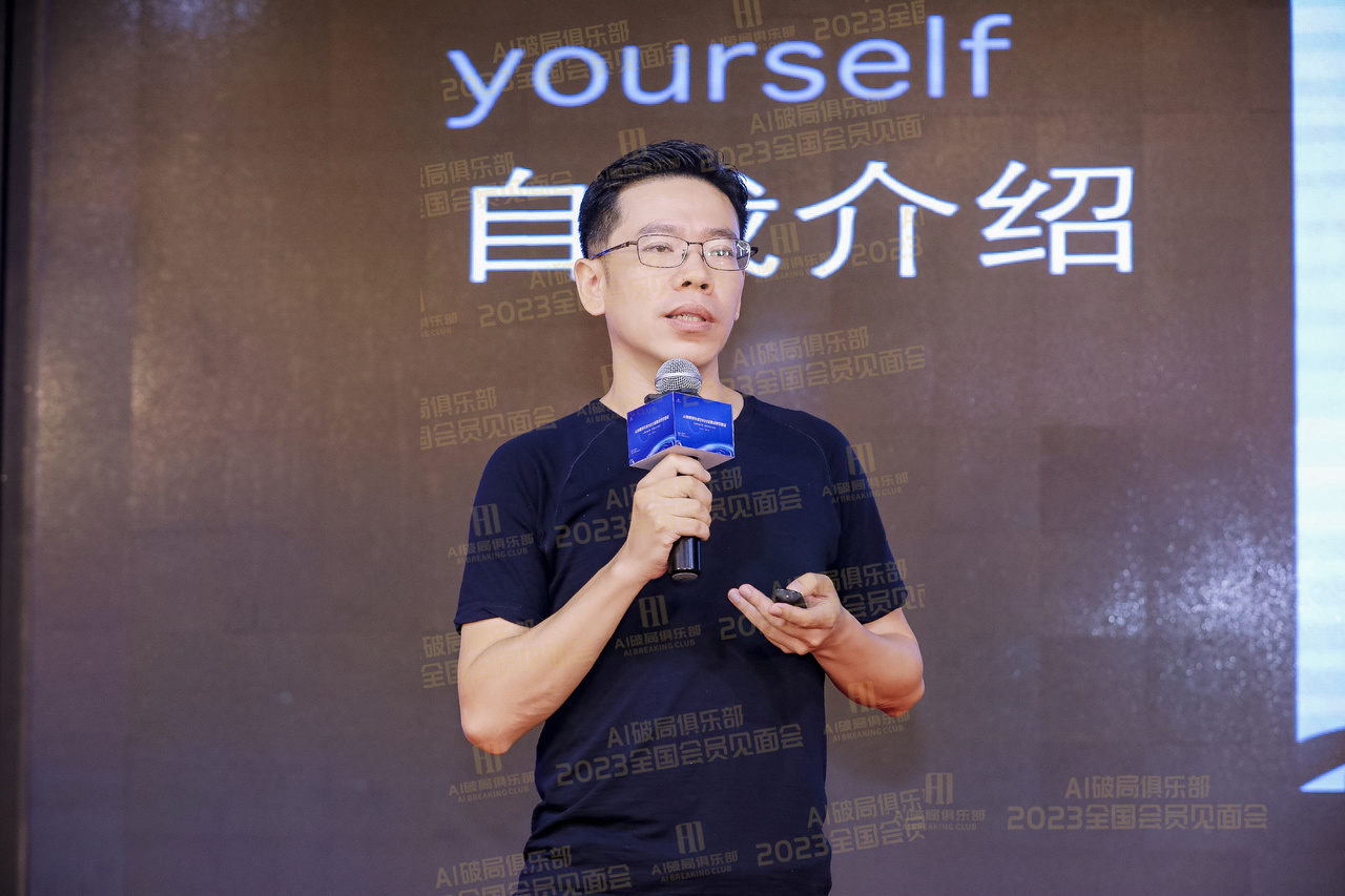 图片展示的是2023年AI破局线下大会中，胡明校长在熊猫同学AI主题演讲的场景。画面中胡明校长身着黑色T恤，手持麦克风和手机，背景为深色，上方有“2023全国会员见面会”字样，右侧大屏幕上显示“yourself 自我介绍”。画面左下角有“AI破局俱乐部 2023全国会员见面会”标识。该图片与上下文紧密相关，直观呈现了胡明校长在大会上的演讲场景。