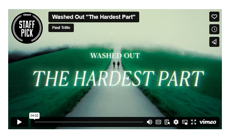 图片展示的是音乐视频《The Hardest Part》的封面,由Washed Out乐队制作。画面中,一条蜿蜒的白色小路延伸至远方,两侧是绿色的草地,路中央有两个人影。画面顶部有“Washed Out 'The Hardest Part'”及“Paul Trillo”字样,左上角有“STAFF PICK”标识。右上角有心形、钟表、喇叭图标。底部有播放按钮、时间显示“04:02”及Vimeo标志。该图片与上下文介绍的视频内容相契合,直观呈现了视频主题及风格。