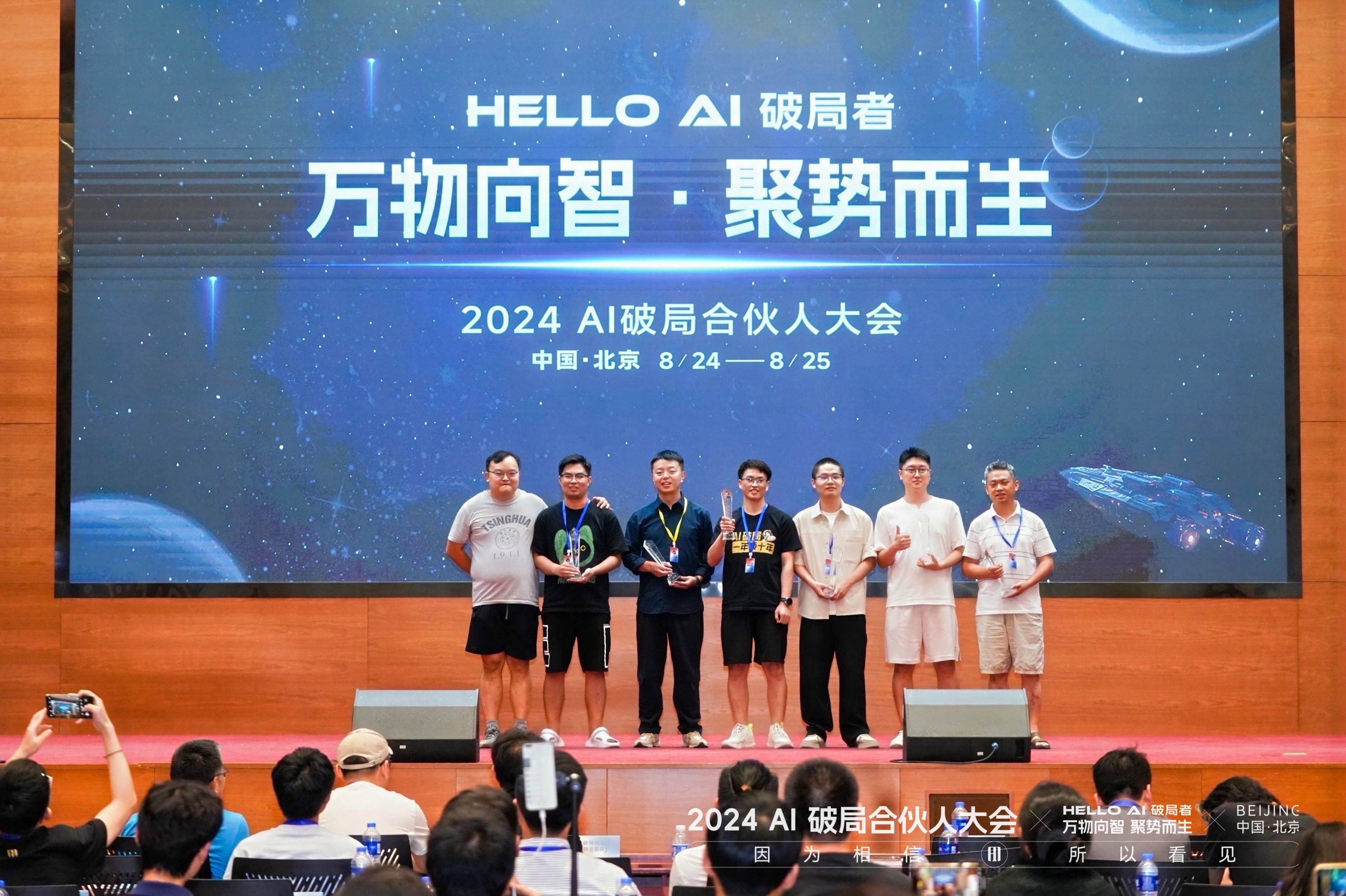 图片展示的是2024 AI破局合伙人大会现场。背景大屏幕上显示“HELLO AI 破局者 万物向智·聚势而生 2024 AI破局合伙人大会 中国·北京 8/24——8/25”。画面中有八位身着不同服装的人员站成一排，其中两人手持奖杯，其他人则展示着奖牌或奖杯。下方有“2024 AI破局合伙人大会”字样。此图与上下文提到的领奖内容相呼应，直观呈现了获奖场景。