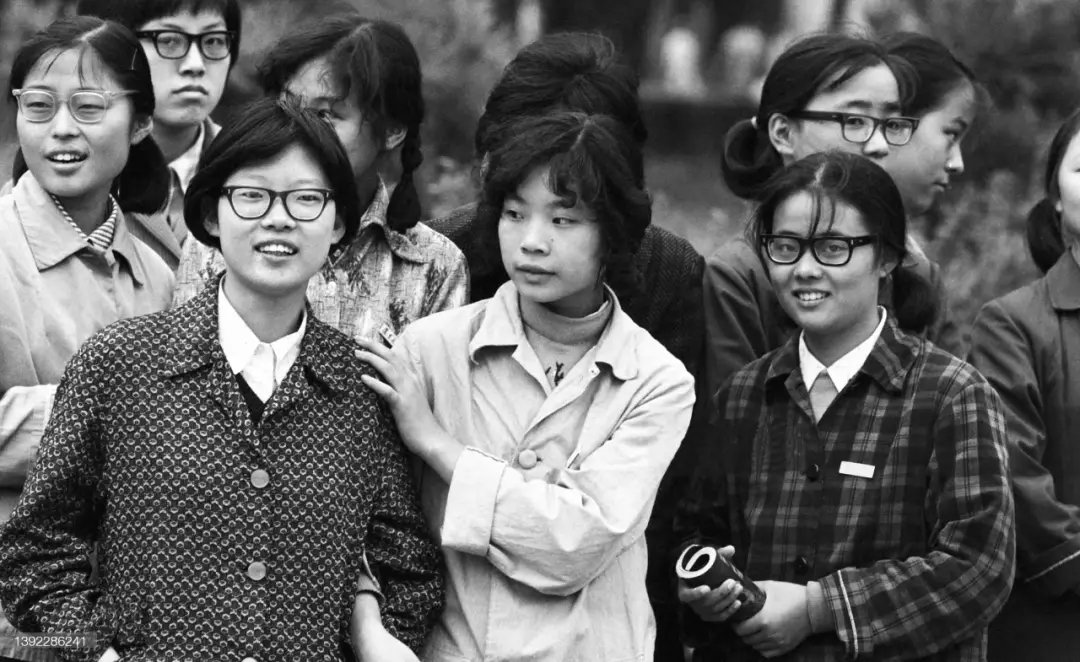图片是一张黑白老照片，画面中有多位穿着朴素的年轻女性，她们神态各异，有的面带微笑，有的神情平静。部分人戴着眼镜，衣着款式具有年代感。这张图片处于介绍老照片上色的内容中，位于提及使用美图秀秀软件【图片上色】功能之后，展示的是上色前的老照片状态，与上下文介绍的老照片上色操作相呼应，直观呈现了上色处理的对象原貌。