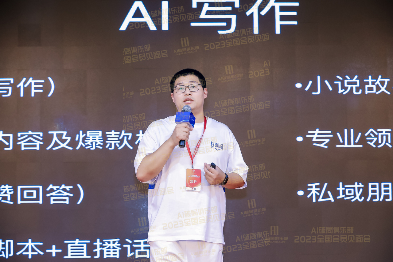 图片展示的是2023年AI破局线下大会中，一位在台上演讲的嘉宾。他身着白色短袖，佩戴红色证件，手持麦克风，专注地进行演讲。背景大屏幕上显示“AI写作”及“2023全国会员见面会”等字样，还有“小说故事”“专业领域”“私域朋友”等关键词。该图片与上下文紧密相关，是对刘驴在大会中分享AI时代企业如何找到切入点这一内容的直观呈现。