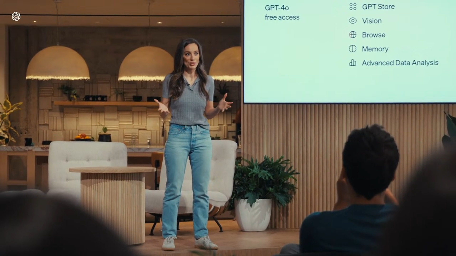 图片中一位女士站在台上，双手张开正在进行讲解，身后屏幕显示“GPT-4o free access”，右侧列出了GPT Store、Vision、Browse、Memory、Advanced Data Analysis等功能。图片与上下文都围绕GPT-4o展开，上下文介绍了GPT-4o的特性、开放范围、价格优势等，图片则直观呈现了GPT-4o免费访问及相关功能，是对GPT-4o介绍的视觉补充。