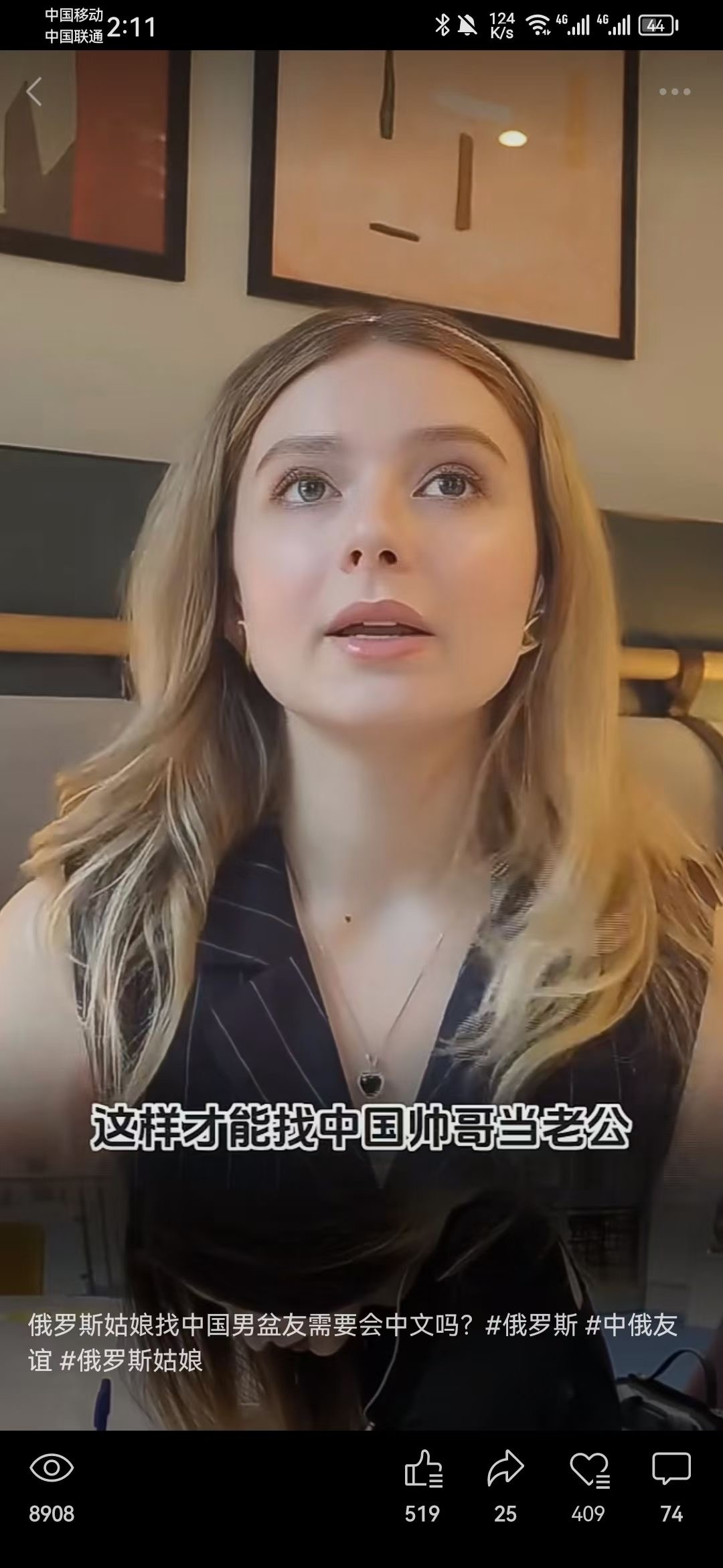 图片展示了一位金发俄罗斯美女,她戴着耳麦,身穿黑色条纹服装,正对着镜头说话。画面下方配有字幕“这样才能找中国帅哥当老公”,底部还有视频话题标签,如“俄罗斯姑娘找中国男盆友需要会中文吗?#俄罗斯 #中俄友谊 #俄罗斯姑娘”。视频播放量为8908,点赞数519,转发25,收藏409,评论74。该图片与文档上下文相关,是文档中提及的“外国美女讲中文”视频的截图示例。