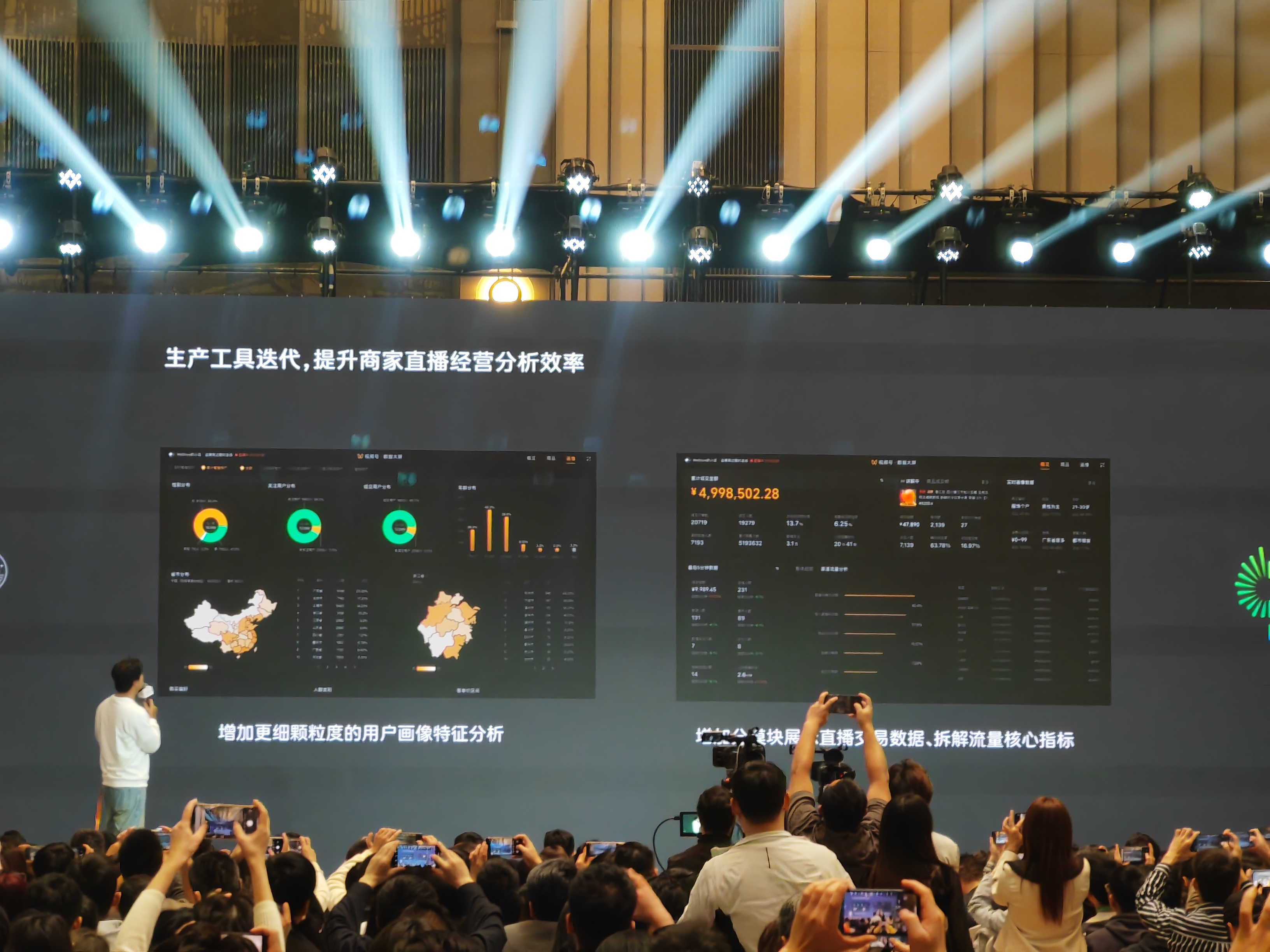 图片展示的是2024「微信公开课」现场,台上演讲者身后的屏幕显示“生产工具迭代,提升商家直播经营分析效率”。屏幕左侧呈现增加更细颗粒度的用户画像特征分析图表,包括环形图和地图等;右侧展示直播交易数据、拆解流量核心指标等内容,屏幕上还显示了金额“¥4,998,502.28”。台下众多观众正举起手机拍摄。此图与上文视频号直播带货分享会中提到的完善后台数据等内容相关。